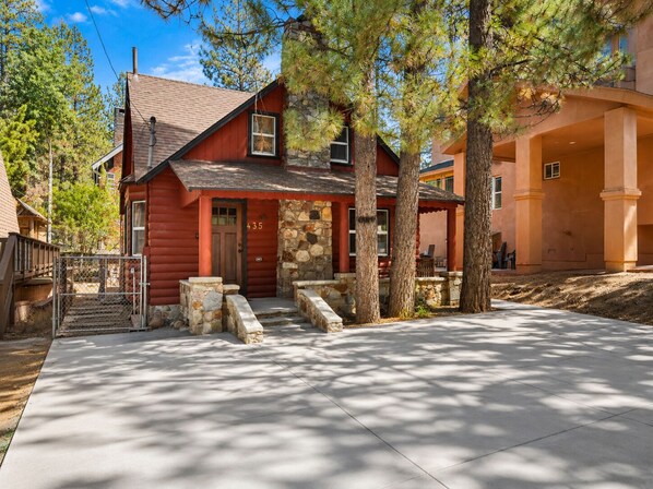 A red log cabin with a stone porch, a stone chimney, and a number 435 on the door.