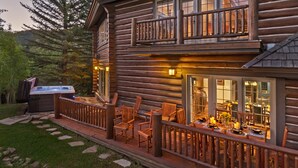 Un chalet en rondins doté d’un bain à remous, d’un espace extérieur aménagé et d’un coin repas éclairé à la bougie.