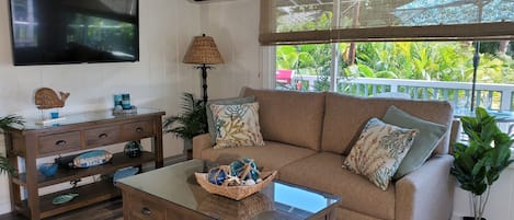 A living room with a sofa, coffee table, TV, and air conditioning unit.