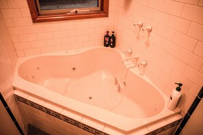 Bathroom features a bathtub with a window above.