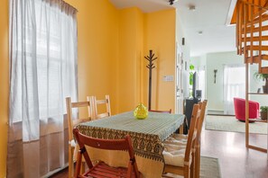 Cozy dining area with a table set for four, featuring a patterned tablecloth and a vase centerpiece.