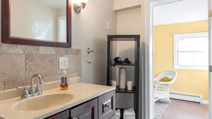 A bathroom with a sink, mirror, towel rack, and shelves with toiletries.