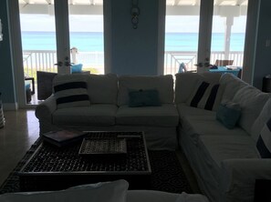 A living room with a white sofa, a coffee table, and a view of the ocean. - Blue Beach Front Home at Resort World (North Bimini)