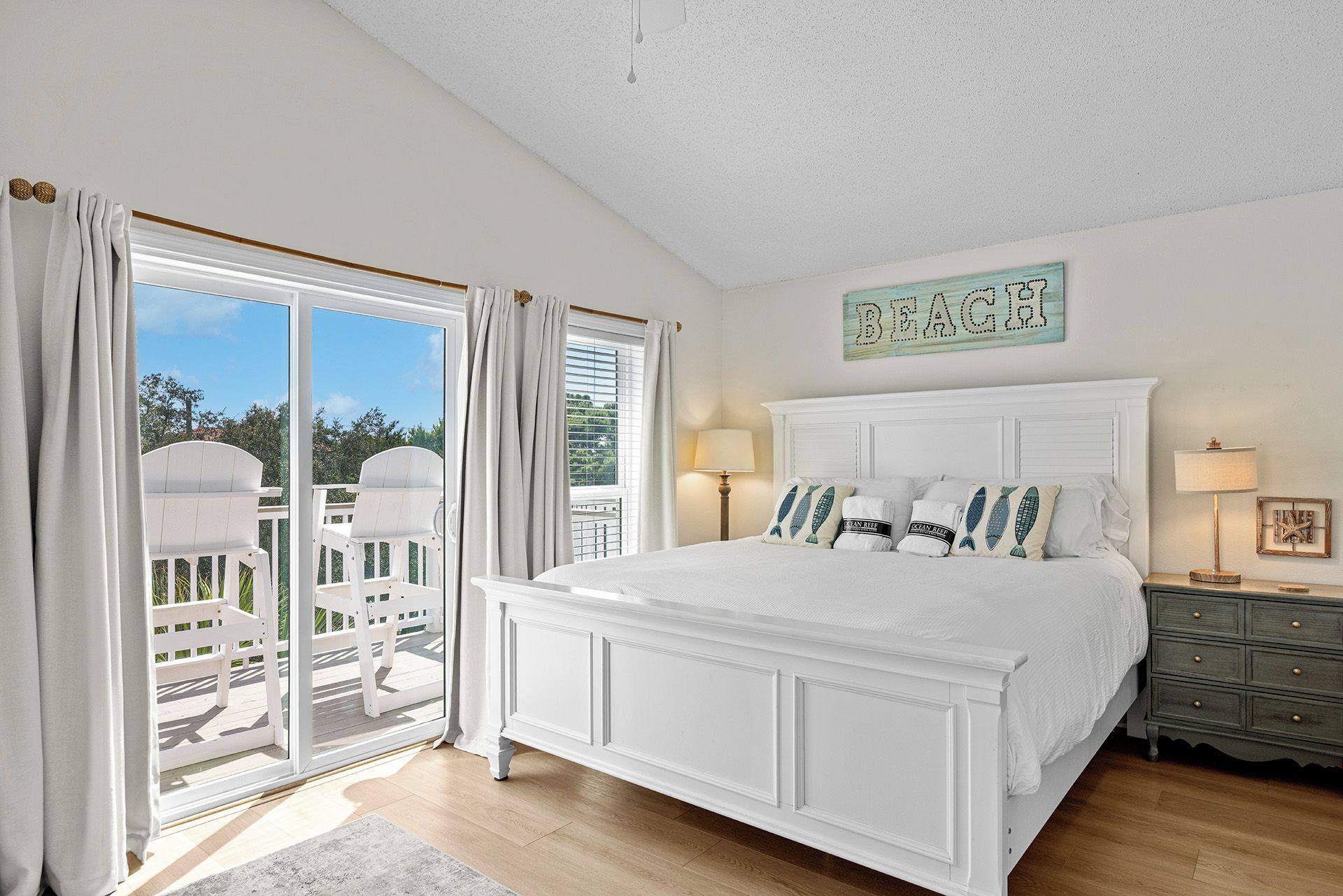 A bedroom with a large bed, a view of the outdoors, and a sign on the wall.