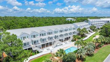 A large resort with multiple buildings, a swimming pool, and lush greenery.