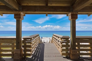 A wooden boardwalk leading to a beach with clear skies.