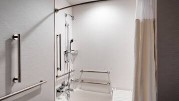 A modern bathroom with a walk-in shower, grab bars, and a white bathtub.