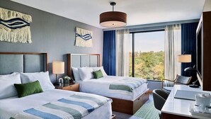 A hotel room with two beds, a desk, a chair, a lamp, and a view of trees. - Lockwood Hotel (Waterville)