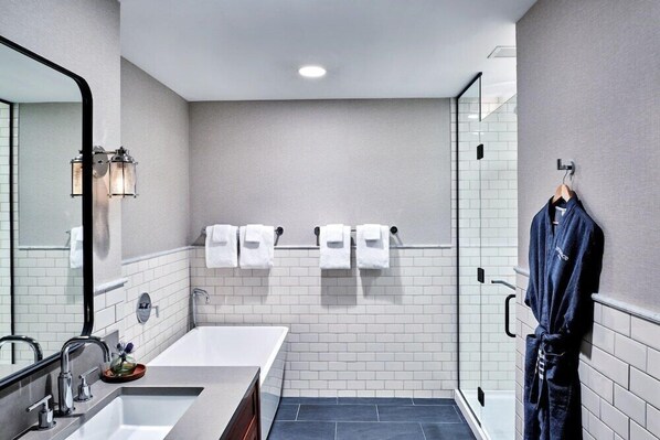 A modern bathroom with a large mirror, two sinks, a bathtub, and a glass shower enclosure.