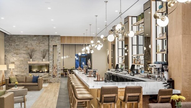 A modern kitchen with a long bar area, stone walls, and a fireplace. - Lockwood Hotel (Waterville)