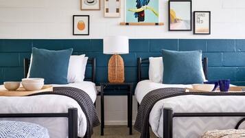 A room with two beds, a wall-mounted lamp, and framed artwork.