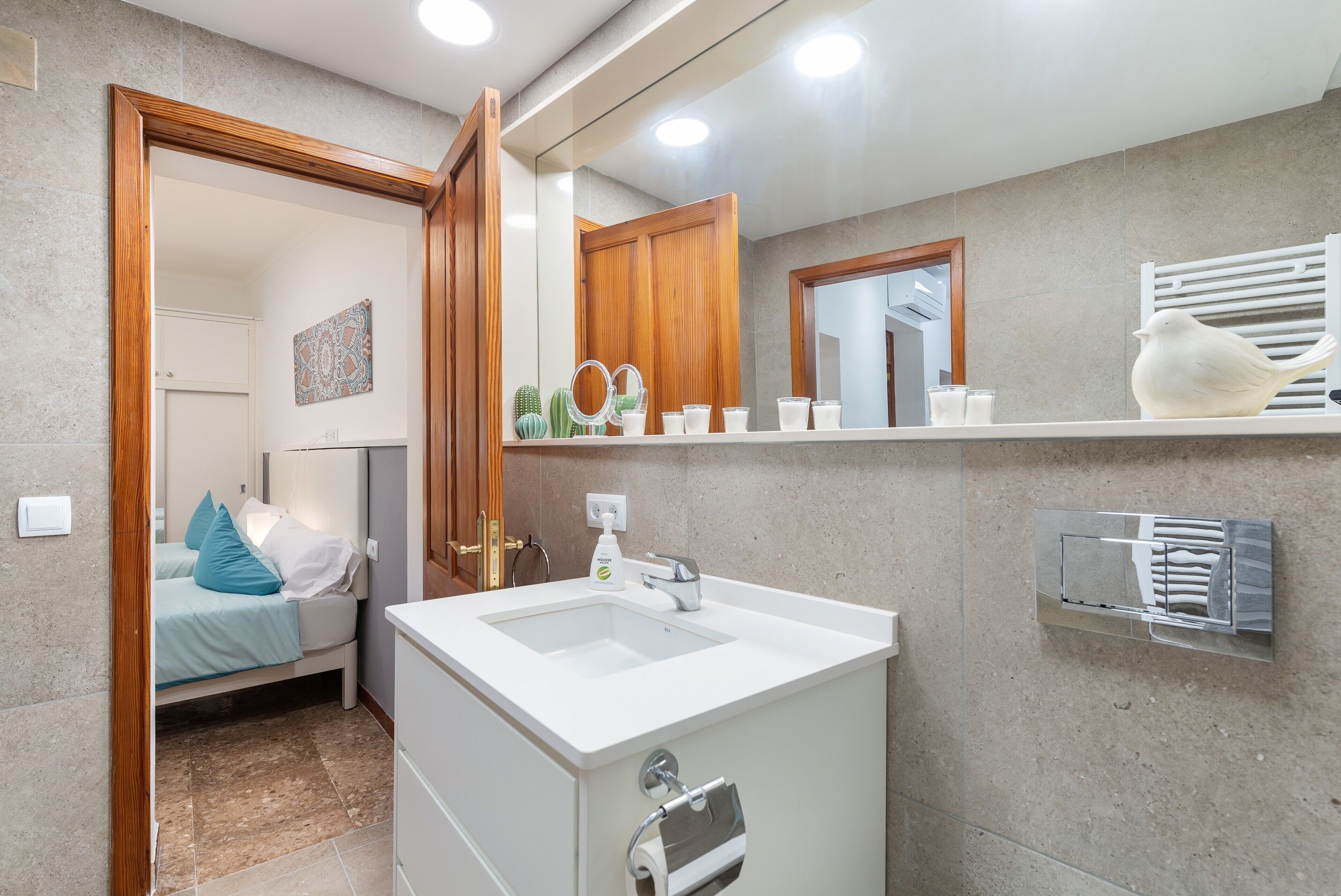 A modern bathroom with a sink, mirror, and towel rack.