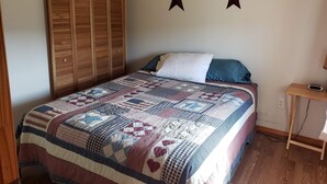 Une chambre avec une armoire en bois, une couvre-lit matelassé et trois décorations en forme d’étoile accrochées au mur.