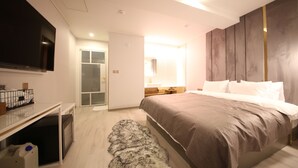Ein modernes Schlafzimmer mit einem großen Bett, einem an der Wand montierten Fernseher, einem Schreibtisch und einem Kleiderschrank.