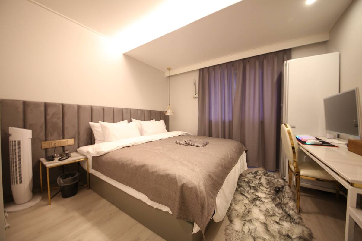 Una habitación de hotel con cama, escritorio, silla, televisor y calefacción.