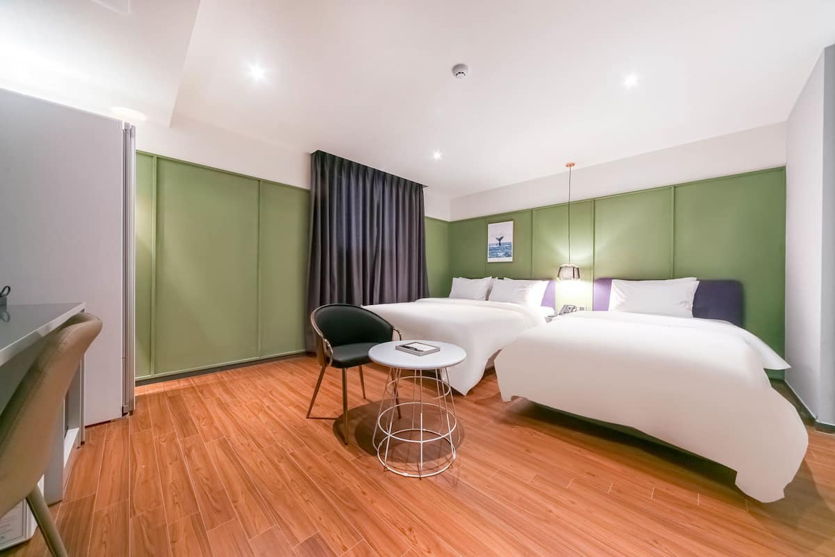 Ein Hotelzimmer mit zwei Betten, einem Schreibtisch, einem Stuhl und einem kleinen Tisch.