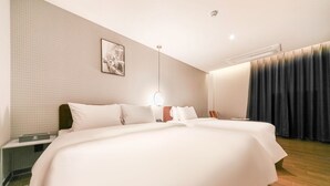 A hotel room with a large bed, a bedside table, a wall-mounted picture, a ceiling light, and a window with curtains. - Pohang Brown Dot Hotel (Pohang)