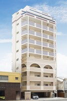 Un edificio de varios pisos con un patio central, balcones y un estacionamiento.