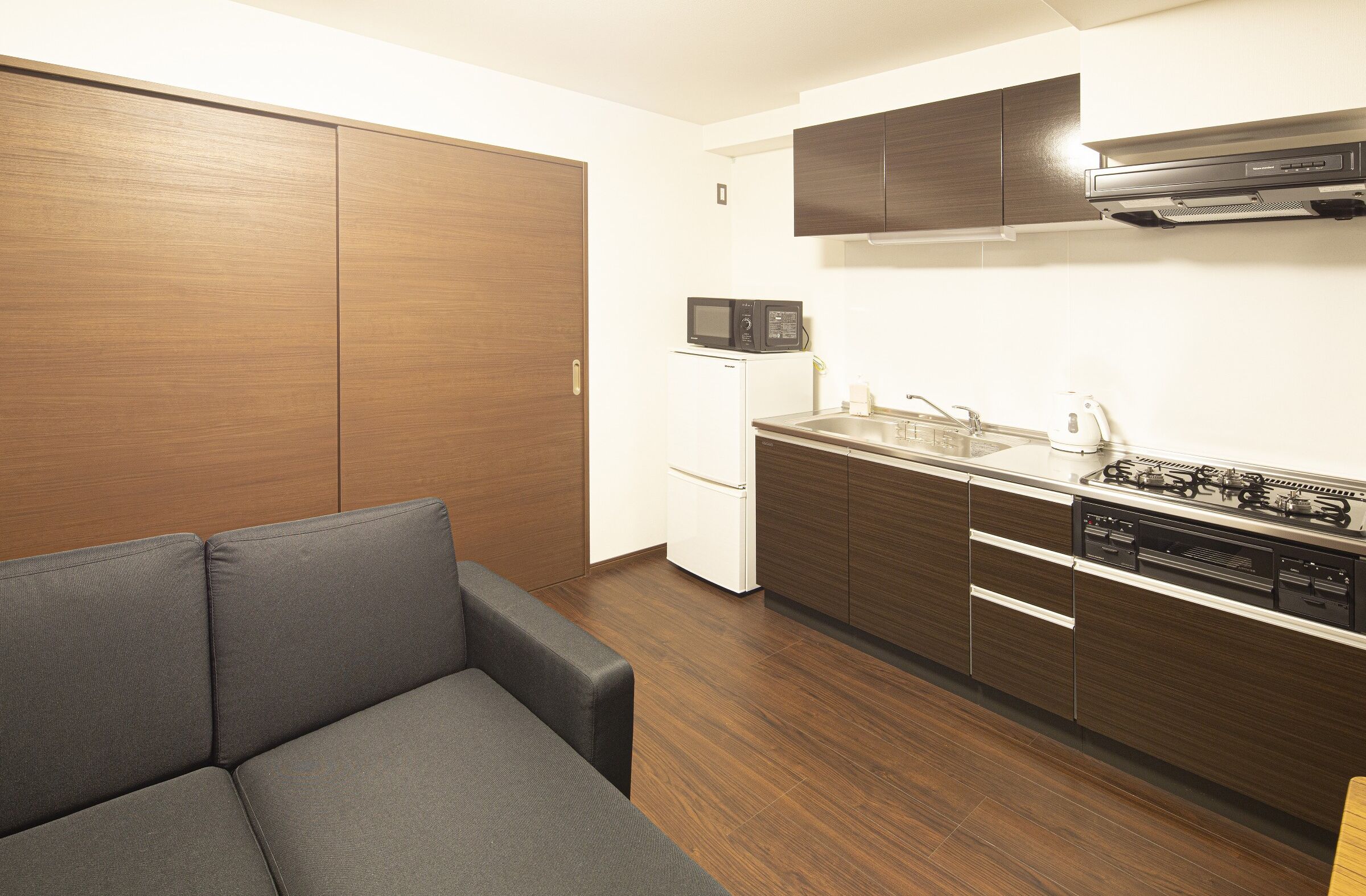 Cocina pequeña con microondas, estufa y refrigerador blanco.