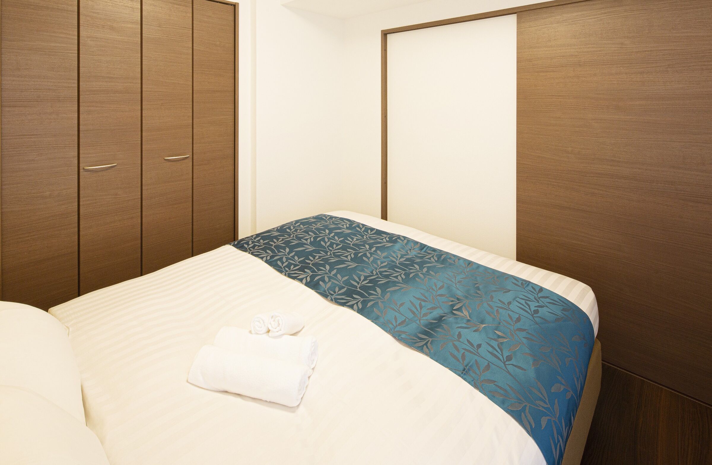 Habitación de hotel con cama, armario y un espejo grande.