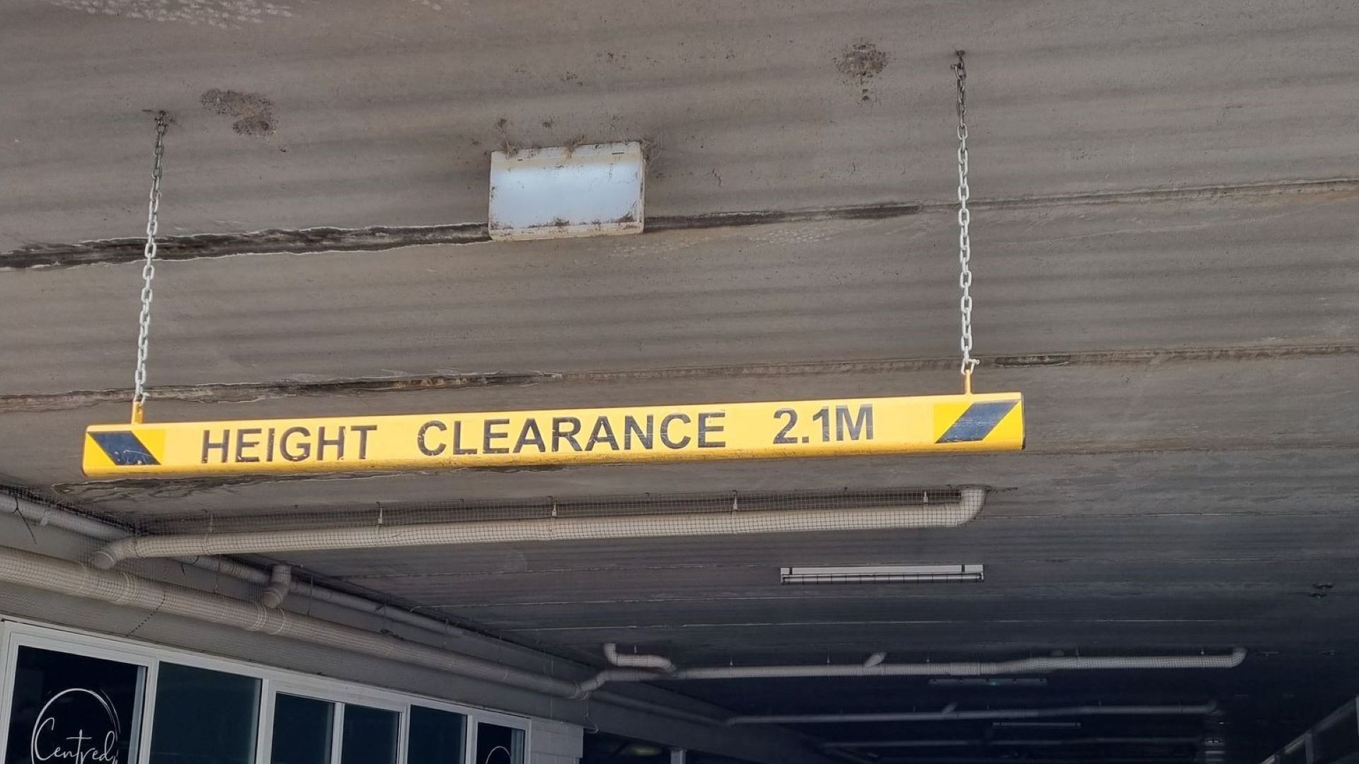 A yellow height clearance sign indicating a limit of 2.1 meters.
