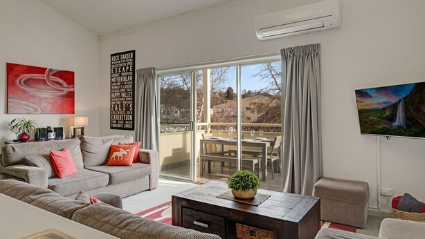 A modern living room with a grey sofa, a coffee table, and a TV on the wall. - Razorback 15 - Central Jindabyne CBD Unit (Jindabyne)