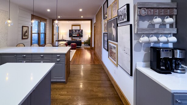 Una cocina moderna con una isla central, suelo de madera y un rincón para el café.