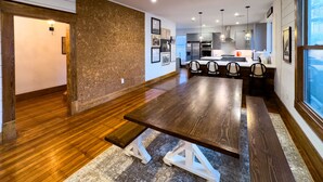 Una cocina moderna con suelo de madera, una zona de comedor con mesa de madera y un ventanal con vistas.