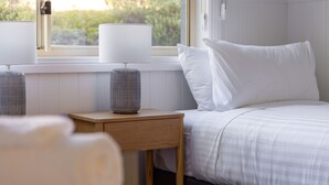 Une chambre à coucher avec un lit, deux lampes de chevet et une fenêtre donnant sur un paysage verdoyant.