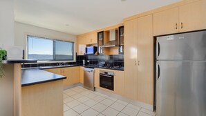 A modern kitchen with wooden cabinets, a stainless steel refrigerator, a microwave, and a dishwasher.