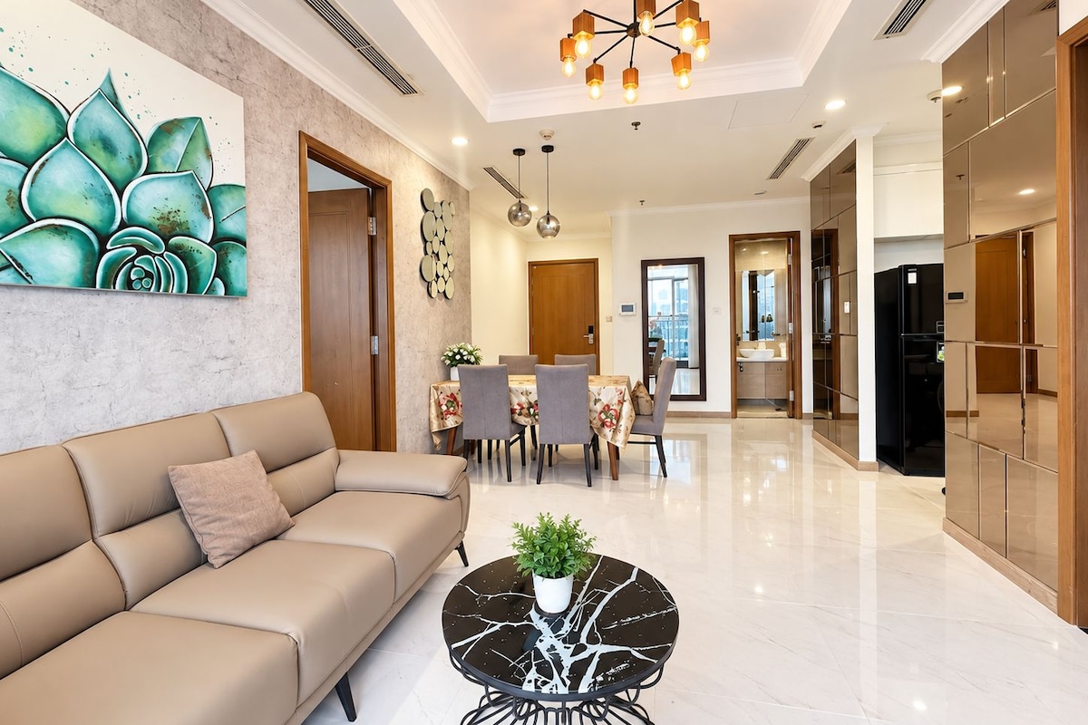 Una sala moderna con sofá, un comedor con sillas y una mesa, y una cocina con armarios.
