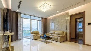 A modern living room with a sofa, two armchairs, a coffee table, and a television. - Vinhomes Luxstay Apartment (Ho Chi Minh City)