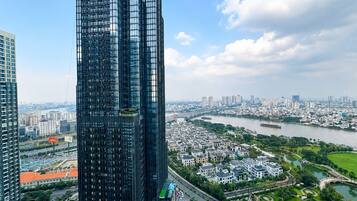 Un edificio de gran altura con fachada de vidrio moderna, rodeado por un río, zonas residenciales y un puente.