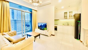 A modern living room with a sofa, TV, and dining area with a kitchen. - Vinhomes Luxstay Apartment (Ho Chi Minh City)