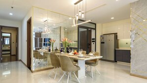 A modern dining area with a glass partition, a stainless steel refrigerator, and a marble accent wall. - Vinhomes Luxstay Apartment (Ho Chi Minh City)