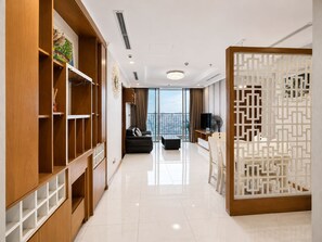 A modern living room with a black sofa, a TV, and a decorative screen. - Vinhomes Luxstay Apartment (Ho Chi Minh City)