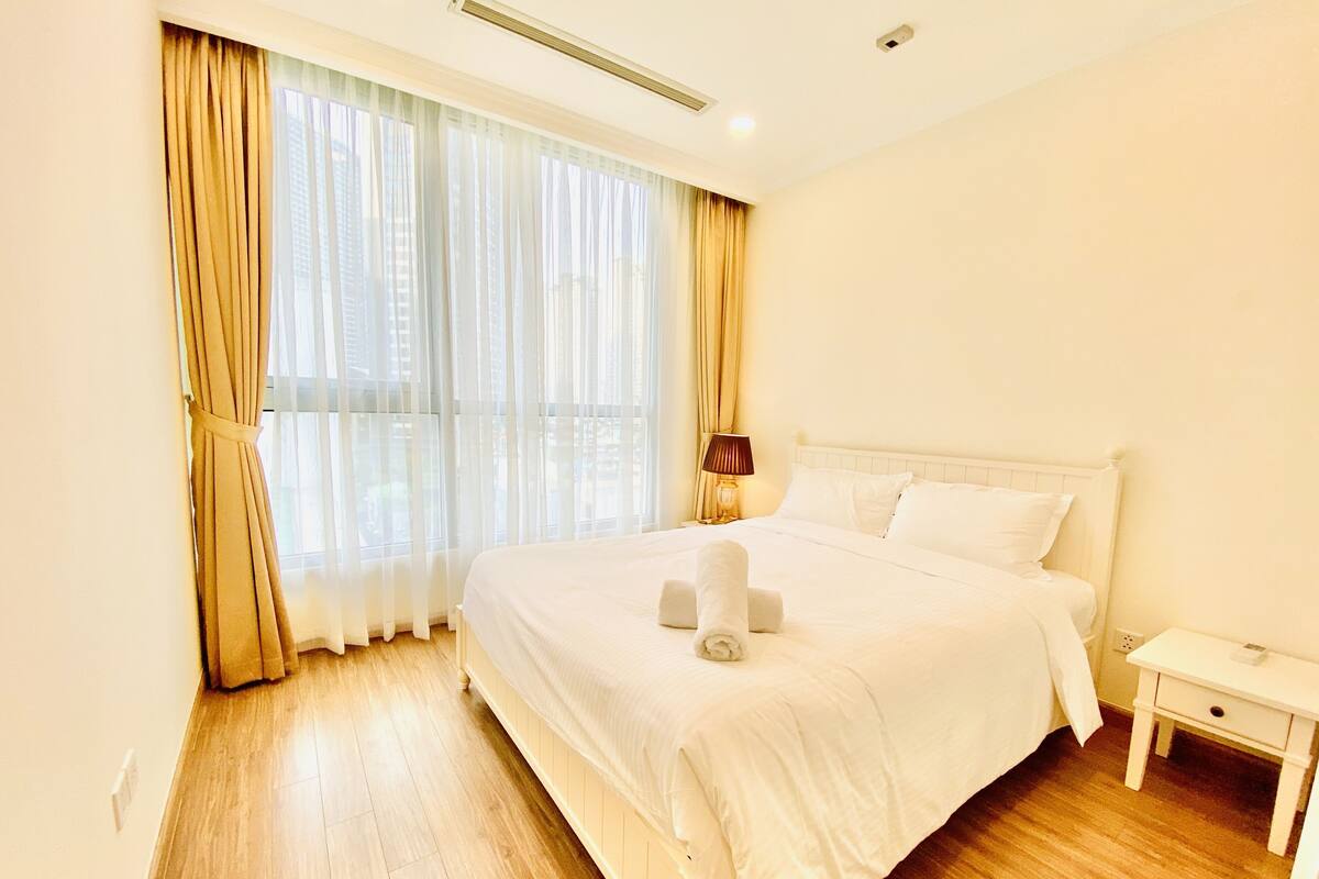 Una habitación de hotel con una cama grande, una mesita de noche y una ventana con cortinas.