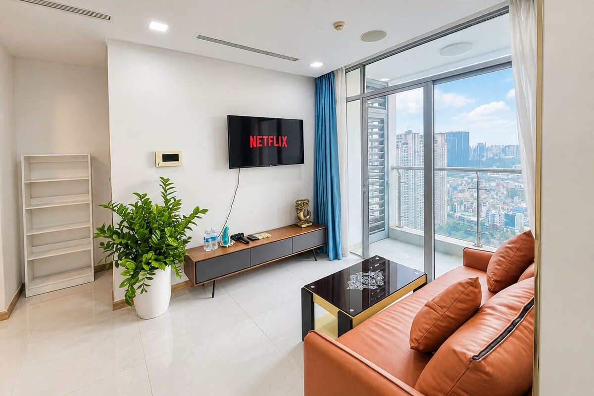 Una sala de estar moderna con un ventanal grande, un televisor de pantalla plana, un sofá, una mesa de centro y una planta.