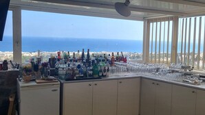 Eine Bar mit Meerblick, ausgestattet mit verschiedenen Flaschen und Gläsern.
