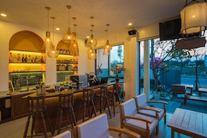 Una zona de bar con sillas de madera y una barra, un ventanal con vistas al exterior y lámparas colgantes.