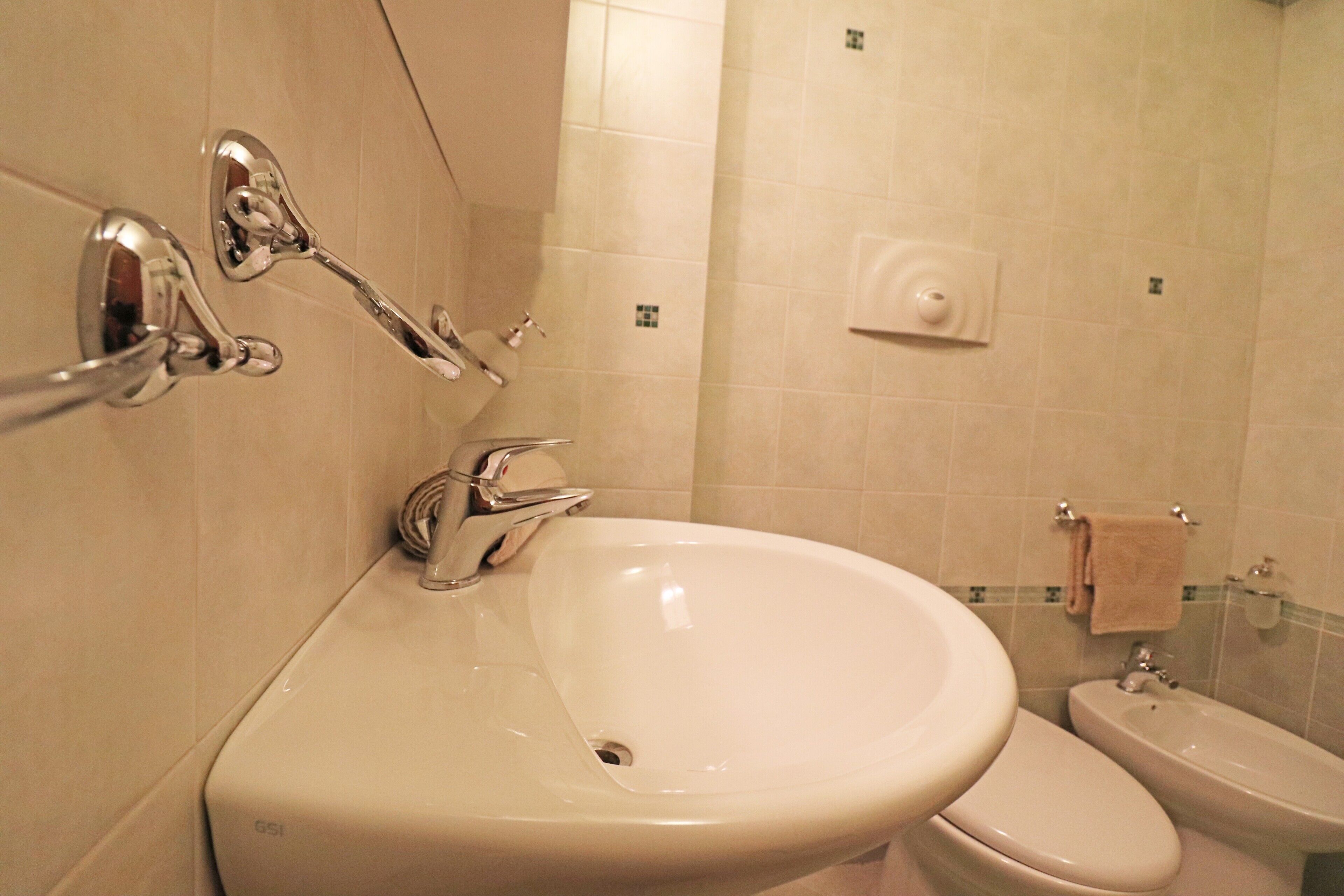 A bathroom with a sink, toilet, and a towel rack.