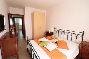 Un dormitorio con cama, armario, mesita de noche y espejo.