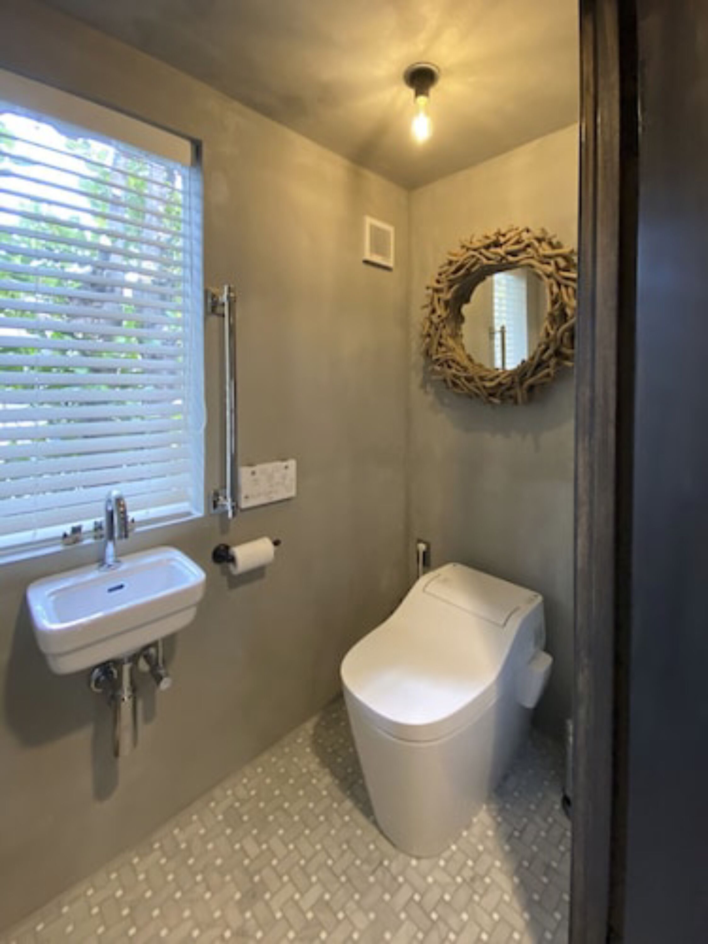 Un baño con lavamanos, inodoro y ventana con persianas.