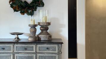 Un aparador de estilo vintage con dos candelabros de vidrio y un arreglo decorativo en la pared de fondo.