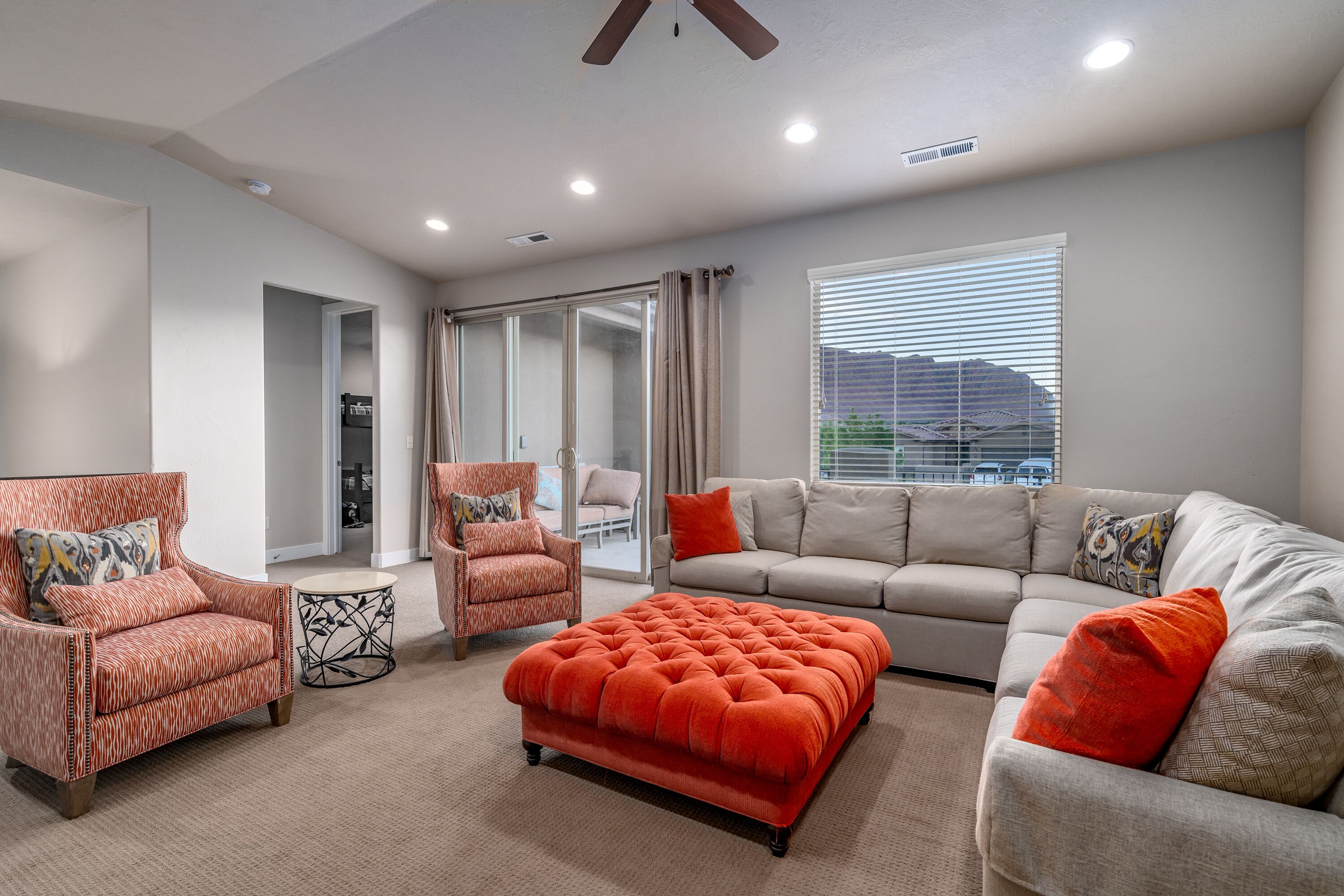 A modern living room with a sofa, two armchairs, a coffee table, and a large ottoman.