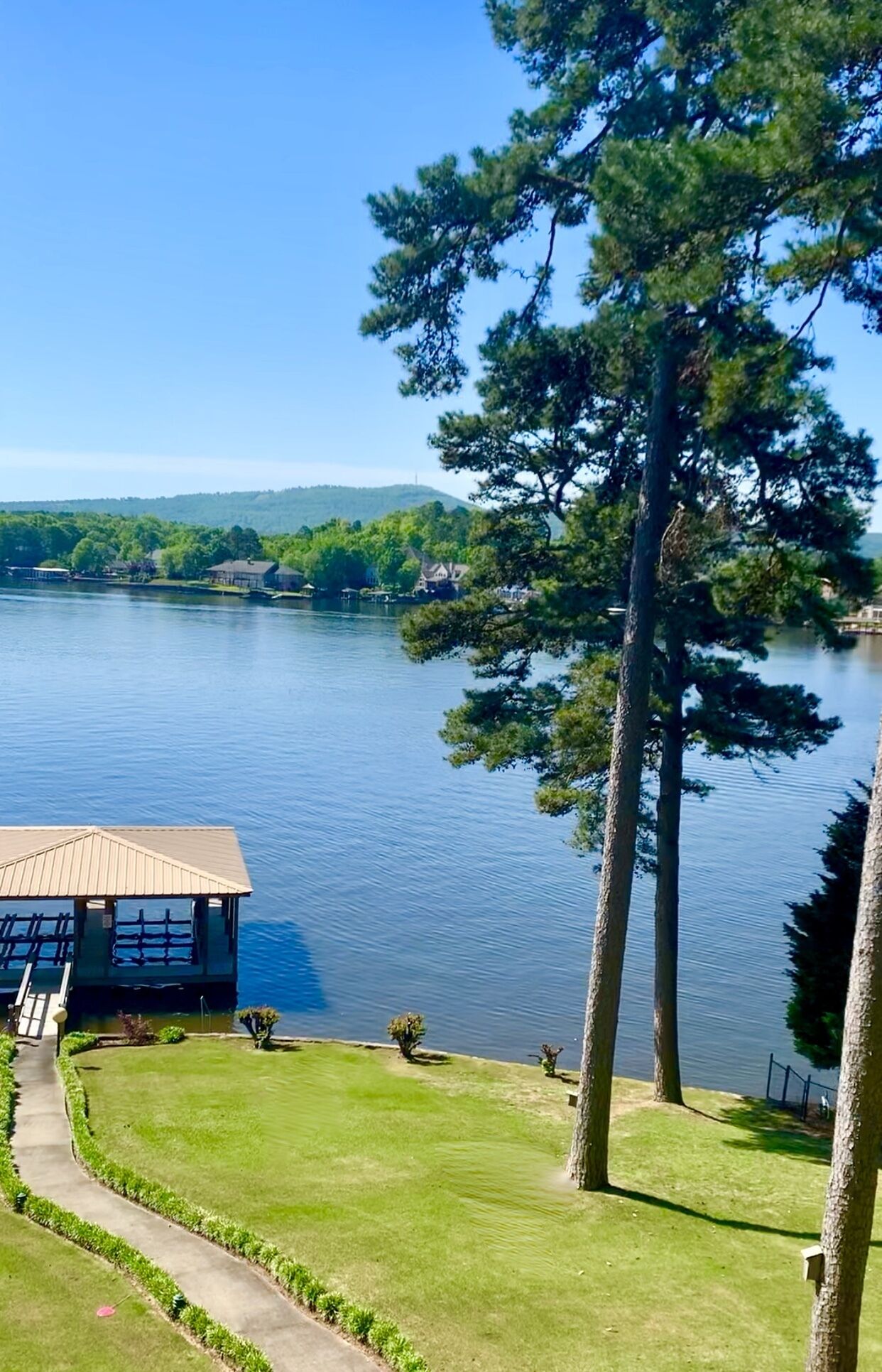 Vista de un lago con un edificio que tiene un muelle y una zona cubierta de césped.