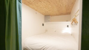A small, compact room with a single bed, a wooden ceiling, and a mirror on the wall. - Theatel Sapporo (Sapporo)
