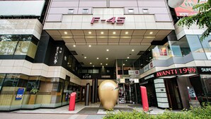 A modern building with a prominent F-45 sign, glass storefronts, and a large golden sculpture in front. - Theatel Sapporo (Sapporo)