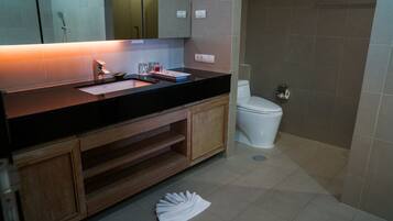 Un baño moderno con encimera negra, armarios de madera, inodoro blanco y zona de ducha.
