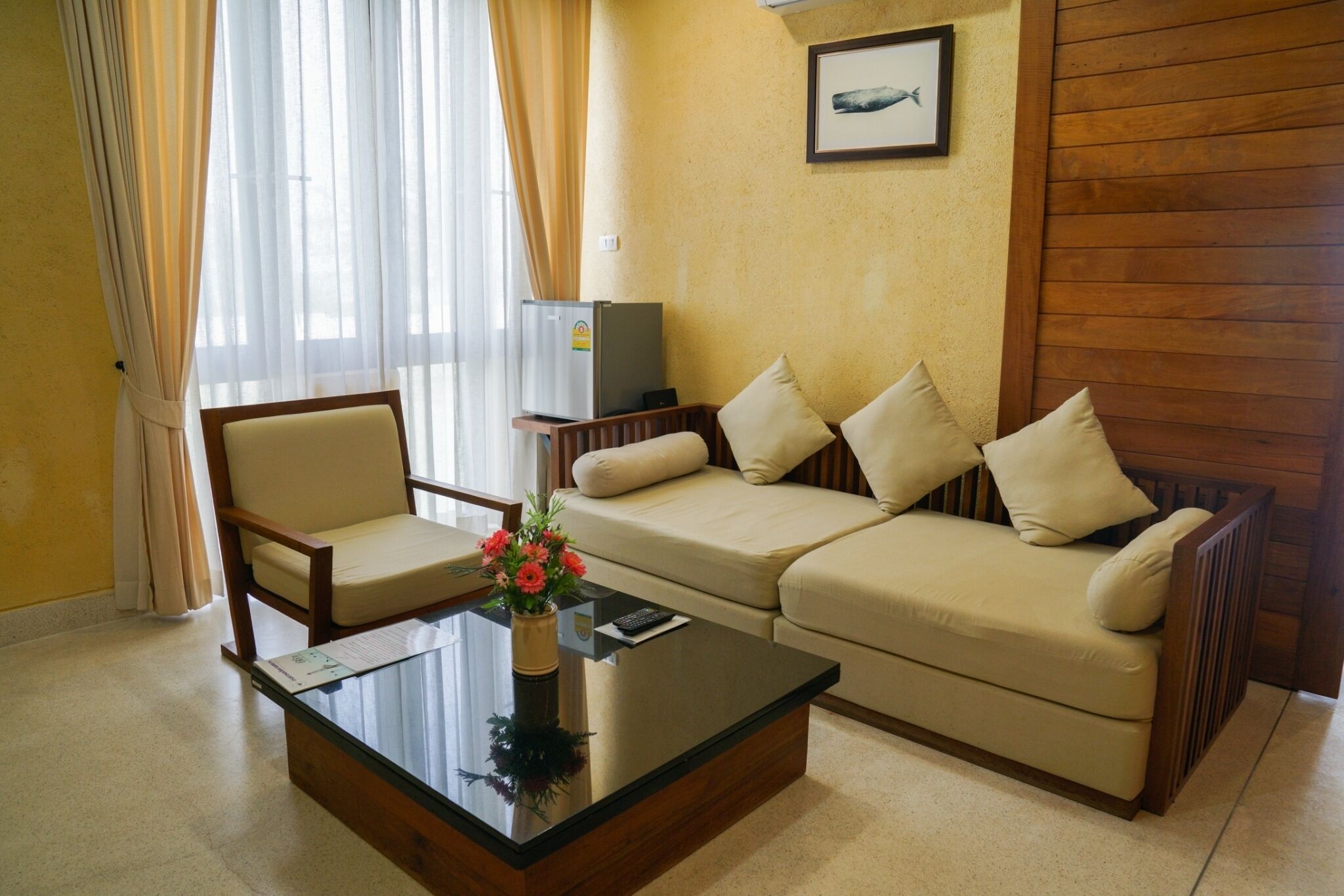 A living room with a sofa, armchair, and a coffee table. There is a TV on a stand and a framed picture on the wall.